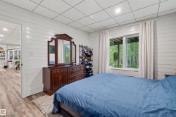 Basement bedroom featuring white horizontal paneling, recessed lighting, and wood-finish flooring - 