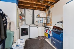 Dedicated laundry area featuring a utility sink, white cabinetry, and exposed ceiling joists - 