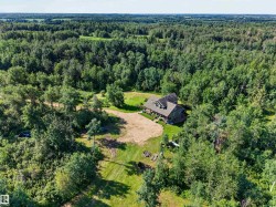 Expansive wooded acreage featuring a large residential structure with a gable roof and dormer window - 