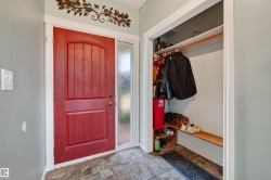 Entryway featuring a paneled red door with sidelight, tile flooring, and a built-in closet with shelving and hanging rod - 