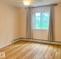 Bright interior space featuring wood-finish flooring, a ceiling fan with integrated lighting, and a large window - 