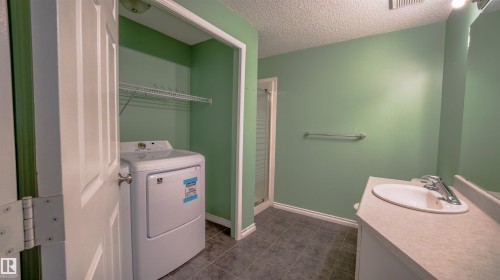 Bathroom featuring a built-in laundry closet with wire shelving, a shower stall with a glass door, a vanity with an integrated sink, and tiled flooring - 29 Campbell Road, Leduc, AB - Indoor