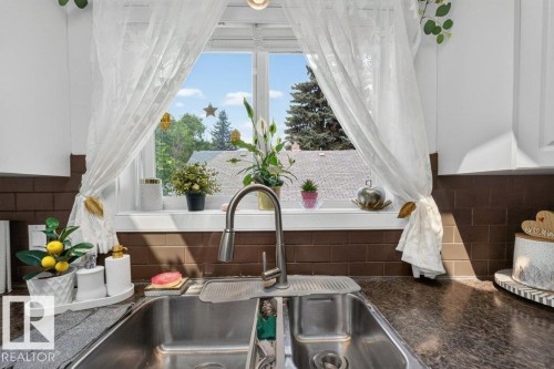 Double basin stainless steel sink with a high-arc faucet, set within a dark mottled countertop - 12219 89 Street Nw, Edmonton, AB - Indoor Photo Showing Bathroom