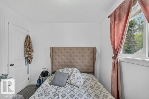White interior walls featuring a window with natural light, a paneled door, and neutral-toned carpeting - 12219 89 Street Nw, Edmonton, AB - Indoor Photo Showing Bedroom