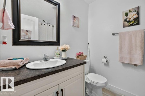 White vanity with dark countertop featuring an oval sink and chrome faucet - 12219 89 Street Nw, Edmonton, AB - Indoor Photo Showing Bathroom