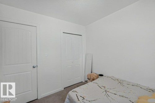 White interior walls with a textured ceiling, featuring a paneled door with a spherical knob and bi-fold closet doors - 12219 89 Street Nw, Edmonton, AB - Indoor Photo Showing Bedroom