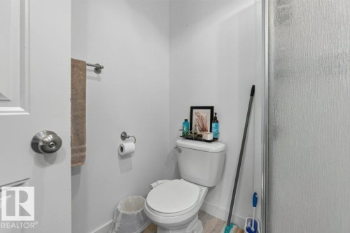 White commode with a ceramic tank and bowl, alongside a textured glass shower enclosure - 12219 89 Street Nw, Edmonton, AB - Indoor Photo Showing Bathroom
