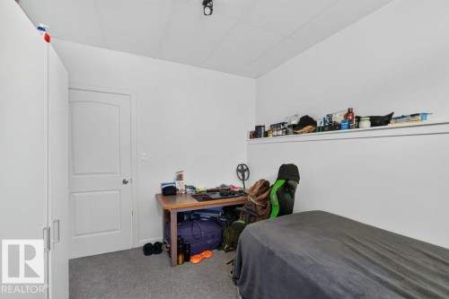 Interior room featuring a white paneled door, light gray carpeting, and a built-in wall shelf - 12219 89 Street Nw, Edmonton, AB - Indoor