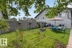 Expansive backyard featuring a partial wood fence, a fire pit area, and a dedicated wooden deck space - 