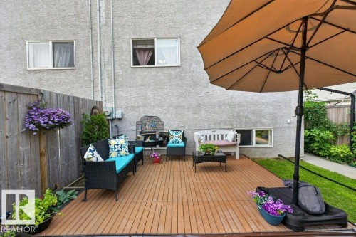 Outdoor decking area featuring wood-finish flooring, a privacy fence, and a stucco exterior - 12219 89 Street Nw, Edmonton, AB - Outdoor With Deck Patio Veranda
