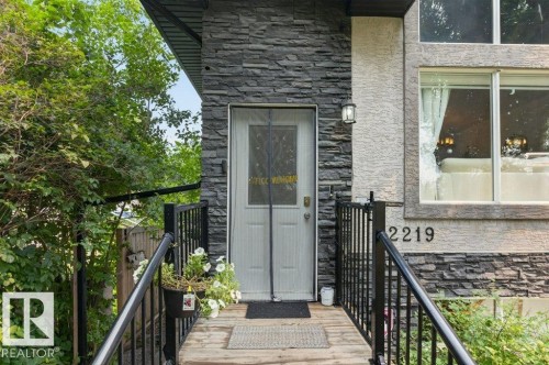 Exterior entrance featuring a stacked stone facade and a wood-finish porch - 12219 89 Street Nw, Edmonton, AB - Outdoor