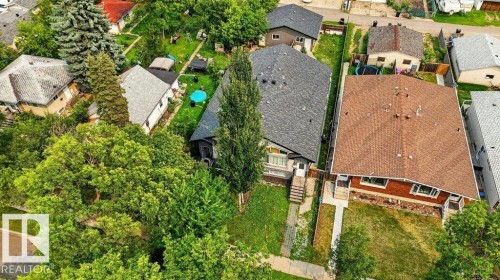 Aerial perspective showcasing a residential property with a dark shingle roof and a light-colored exterior, surrounded by mature trees and green landscaping - 12219 89 Street Nw, Edmonton, AB - Outdoor