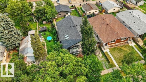 Residential property featuring a dark shingle roof, a front yard with green grass, and mature trees - 12219 89 Street Nw, Edmonton, AB - Outdoor