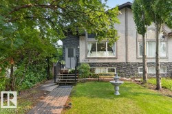 Stucco and stone facade featuring multiple large windows and a covered front entry with stairs - 