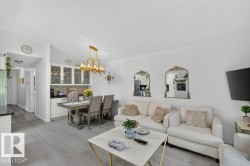 Open-concept living area with light wood-finish flooring, white walls, and recessed lighting - 