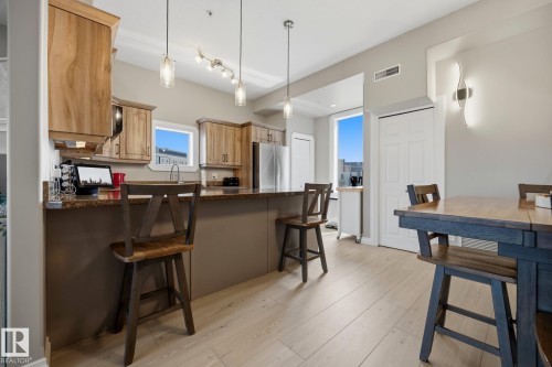 Kitchen featuring wood-finish cabinetry, stainless steel appliances, and a granite countertop island - #201 10625 Kingsway Av Nw, Edmonton, AB - Indoor