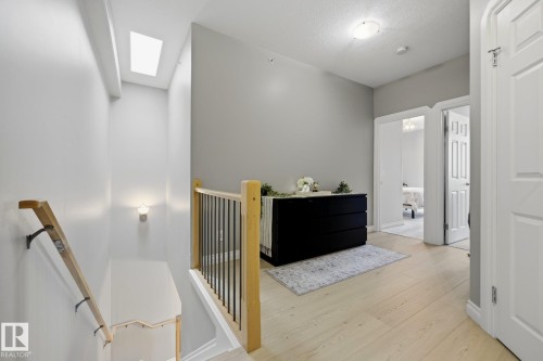 Upper-level landing featuring light wood-finish flooring, a skylight, and white paneled doors - #201 10625 Kingsway Av Nw, Edmonton, AB - Indoor Photo Showing Other Room