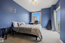 Spacious bedroom featuring vibrant blue walls, light-toned patterned carpet, and abundant natural light from a large window and glass door - 