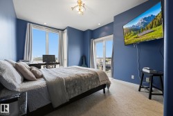 Bedroom featuring a full-light window, sliding glass door with balcony access, wall-mounted television, recessed lighting, and patterned carpet flooring - 