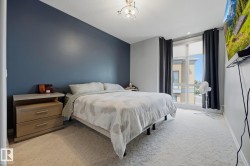 Carpeted bedroom featuring a full-height window with roller shades, a blue accent wall, and a ceiling-mounted light fixture - 