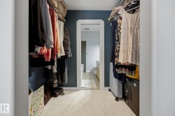 Walk-through closet featuring dark accent walls and light-toned flooring - 