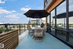 Spacious outdoor balcony with a light blue surface, featuring a glass and metal railing - 