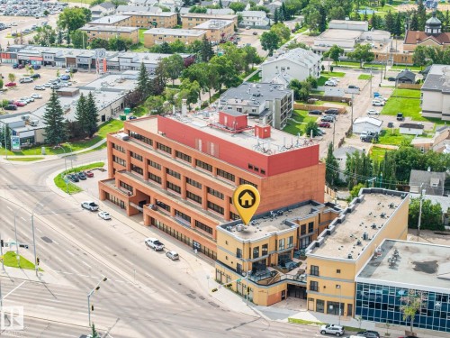 Multi-story commercial building featuring a brick facade with a red upper level, multiple windows, and ground-level retail spaces - #201 10625 Kingsway Av Nw, Edmonton, AB - Outdoor With View