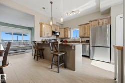 Kitchen featuring light wood-finish cabinetry, stainless steel appliances, and a central island with bar seating - 