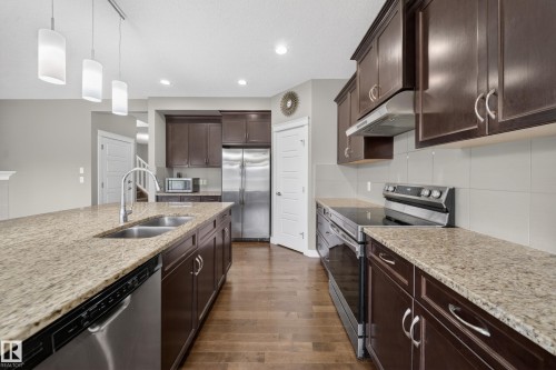 Kitchen featuring wood-finish flooring, dark wood cabinetry, and granite countertops - 3639 15A Street Nw, Edmonton, AB - Indoor Photo Showing Kitchen With Double Sink With Upgraded Kitchen