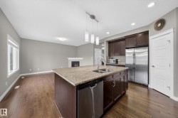 Kitchen island featuring a granite countertop, undermount sink, and pendant lighting - 