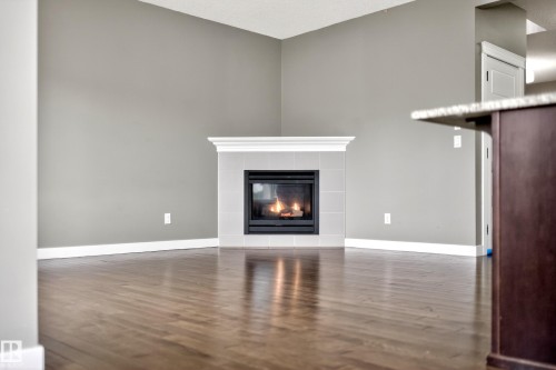 Corner fireplace with a tile surround and substantial mantel - 3639 15A Street Nw, Edmonton, AB - Indoor Photo Showing Living Room With Fireplace