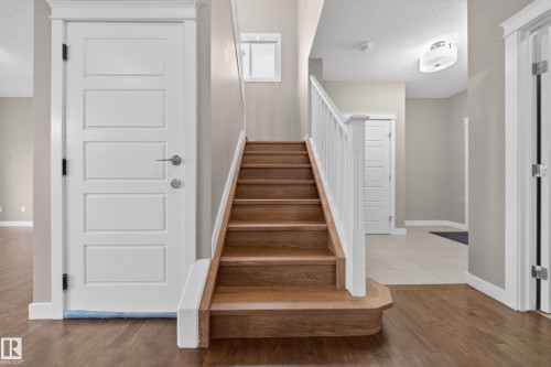 Hardwood staircase with white spindle railing and wood-finish flooring extending into the foreground - 3639 15A Street Nw, Edmonton, AB - Indoor Photo Showing Other Room