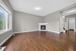 Spacious interior featuring warm wood-finish flooring, a corner fireplace with a white mantel, and vaulted ceilings - 
