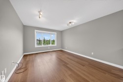 Spacious room featuring wood-finish flooring, light grey walls, and white baseboards - 