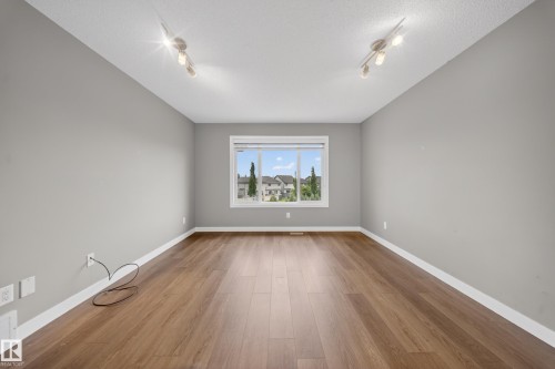 Spacious room featuring wood-finish flooring, light grey walls, white trim, and track lighting fixtures - 3639 15A Street Nw, Edmonton, AB - Indoor Photo Showing Other Room