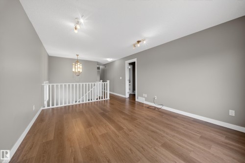 Spacious upper-level landing with wood-finish flooring, light gray walls, and white baseboards - 3639 15A Street Nw, Edmonton, AB - Indoor Photo Showing Other Room