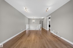 Spacious room featuring wood-finish flooring, light grey walls, white trim, and a white railing - 