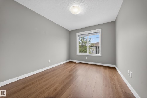 Room featuring wood-finish flooring, neutral gray walls, a white trim package, and a window with a white frame - 3639 15A Street Nw, Edmonton, AB - Indoor Photo Showing Other Room