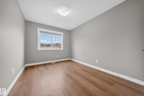Room featuring wood-finish flooring, a white trim baseboard, and light grey painted walls - 3639 15A Street Nw, Edmonton, AB - Indoor Photo Showing Other Room