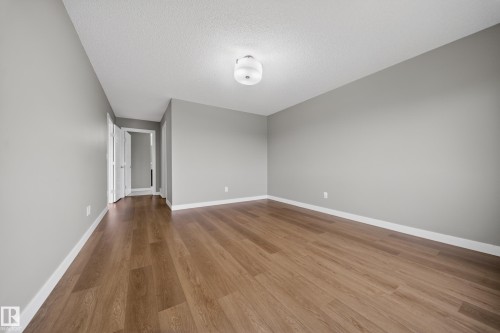 Spacious room featuring wood-finish flooring, light gray walls, white baseboards, and a flush mount ceiling light - 3639 15A Street Nw, Edmonton, AB - Indoor Photo Showing Other Room