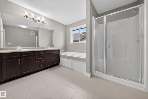 Spacious bathroom featuring a dual vanity with dark wood cabinetry, a large integrated mirror, and a contemporary light fixture - 3639 15A Street Nw, Edmonton, AB - Indoor Photo Showing Bathroom