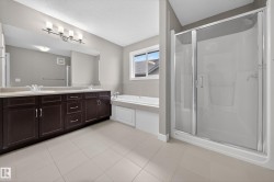 Spacious bathroom featuring a dual vanity with dark wood cabinetry, a large integrated mirror, and a contemporary light fixture - 