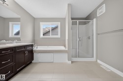 Spacious bathroom featuring a double vanity with dark wood cabinetry, a built-in bathtub, a stand-up shower with a glass enclosure, and light-colored tile flooring - 