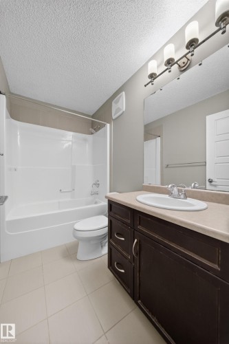 Contemporary bathroom featuring a dark wood-finish vanity with a beige countertop, an undermount sink, and a chrome faucet - 3639 15A Street Nw, Edmonton, AB - Indoor Photo Showing Bathroom