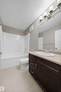 Contemporary bathroom featuring a dark wood-finish vanity with a beige countertop, an undermount sink, and a chrome faucet - 