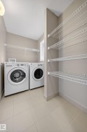 Dedicated laundry room featuring light-toned walls, tile flooring, and integrated wire shelving for storage - 