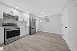 Contemporary kitchen featuring white cabinetry, stainless steel appliances, marble-look backsplash, and light wood-finish flooring - 