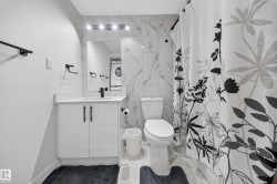 Bathroom featuring a white vanity with a solid surface countertop, matte black fixtures, a wall-mounted mirror, and white tile flooring - 