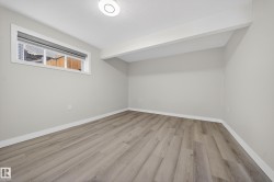 Room featuring wood-finish flooring, light grey walls, white trim, and a horizontal window with a privacy blind - 