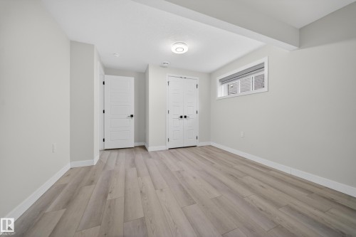 Spacious room featuring wood-finish flooring, light grey walls, and white trim - 3639 15A Street Nw, Edmonton, AB - Indoor Photo Showing Other Room